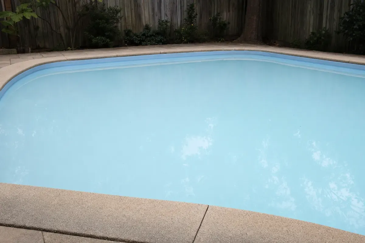 Backyard pool with pale, cloudy water after a mineral top-up — AI-generated illustration
