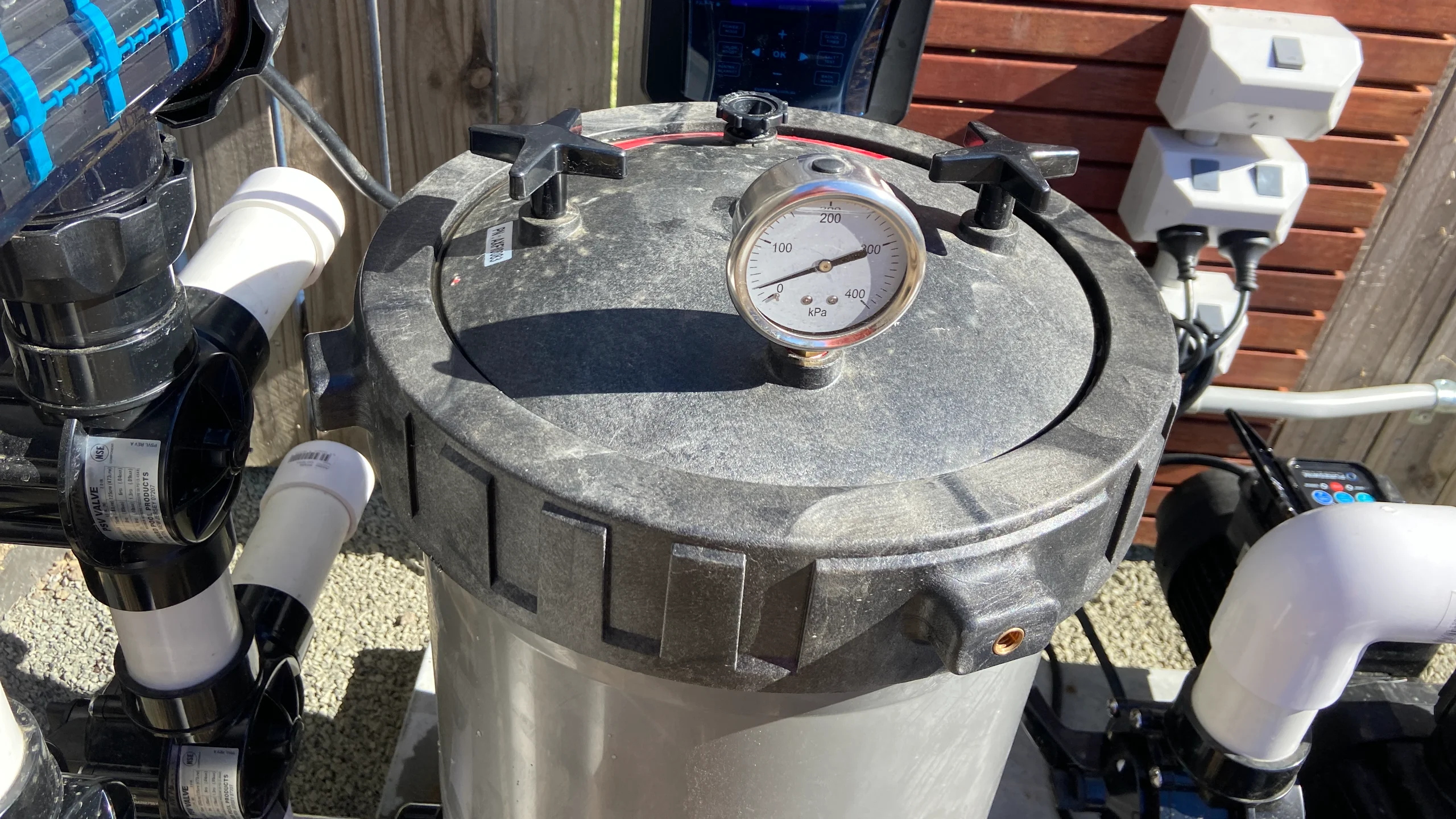Pool cartridge filter with pressure gauge reading in kPa beside pump and equipment plumbing