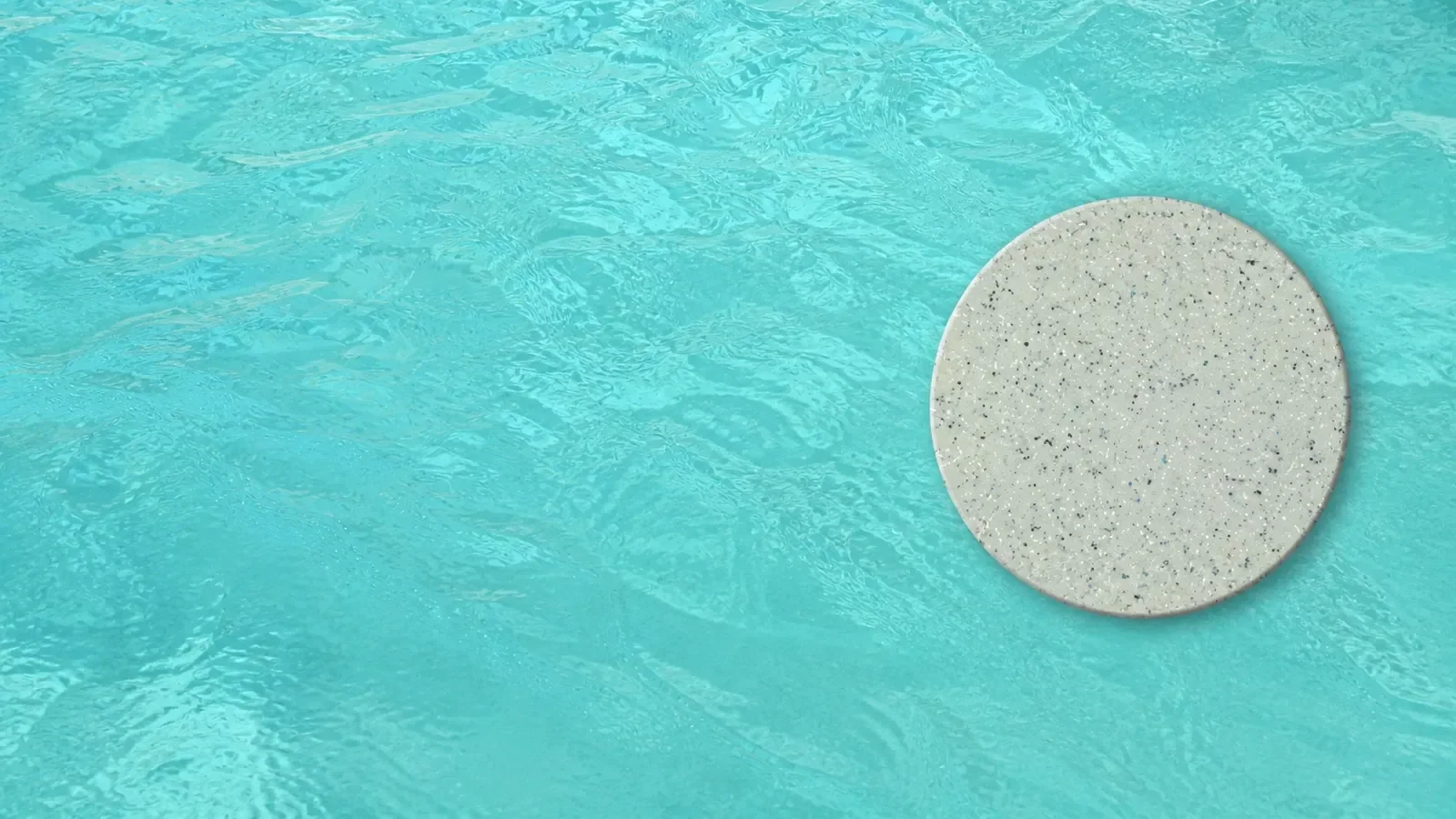 Crystalite pool colour showing turquoise water with a speckled stone step marker near the surface