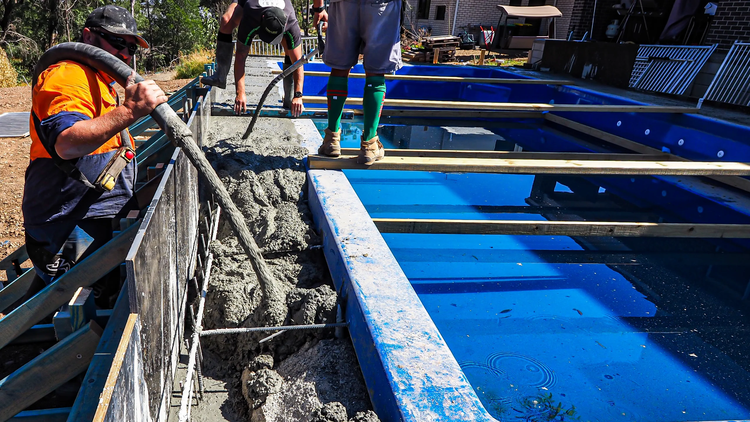 MFP Easy team pouring a concrete bond beam over steel reinforcement around the rim of a blue fibreglass shell