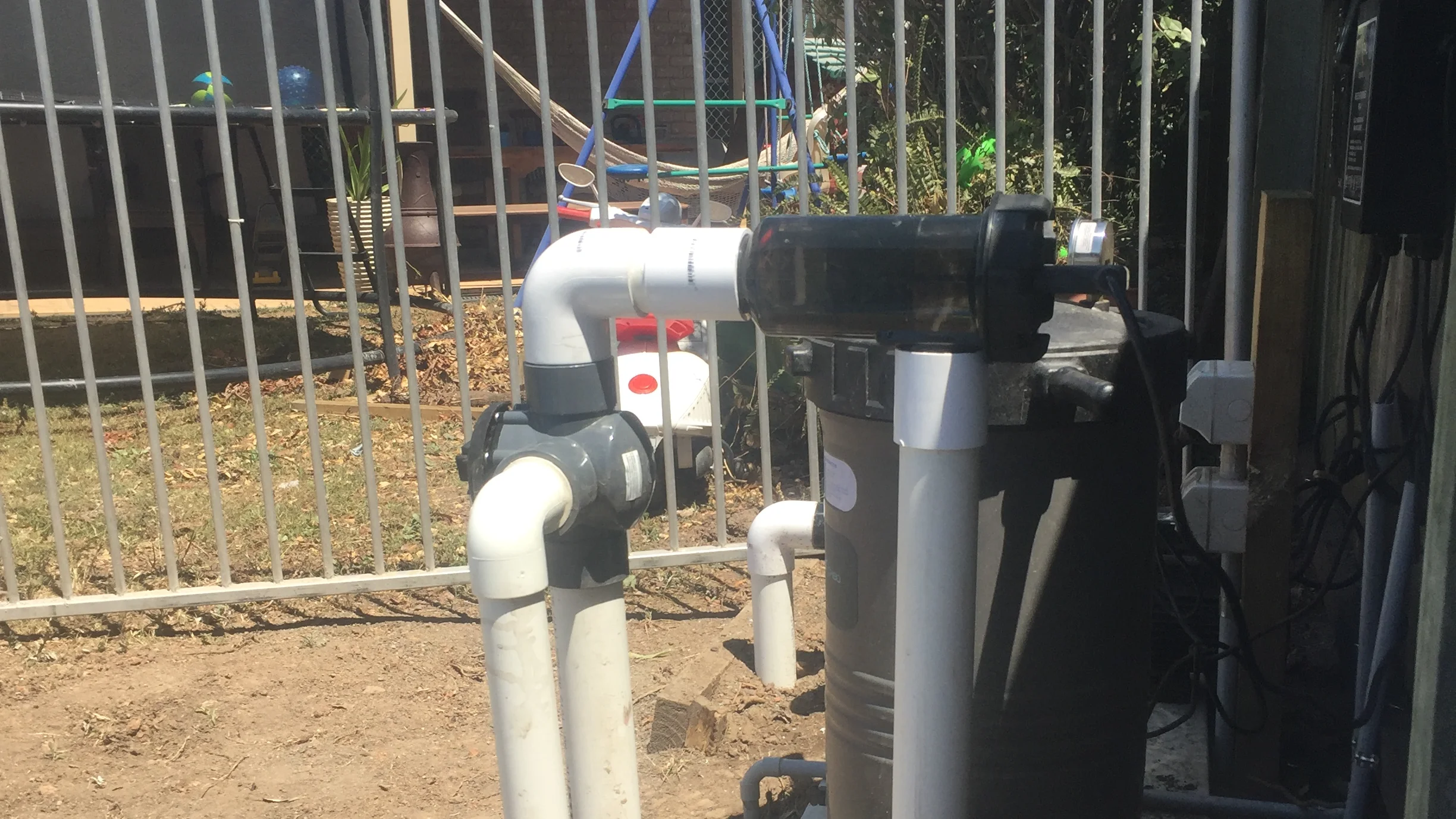Salt chlorinator control box and clear electrolytic cell plumbed into the white filtration line beside a fibreglass pool