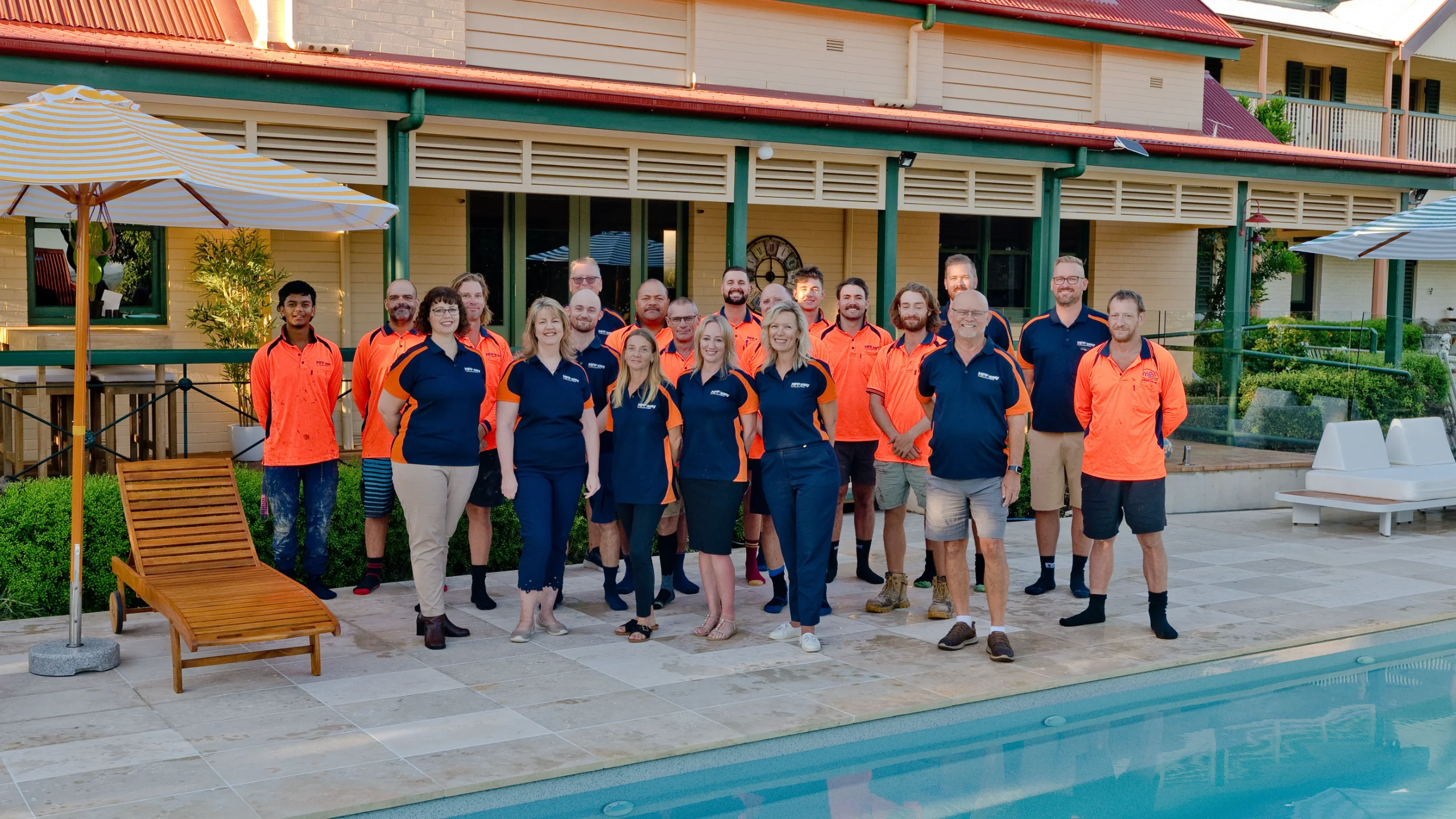 The MFP Easy team in orange and navy uniforms gathered poolside for a choosing-a-builder guide