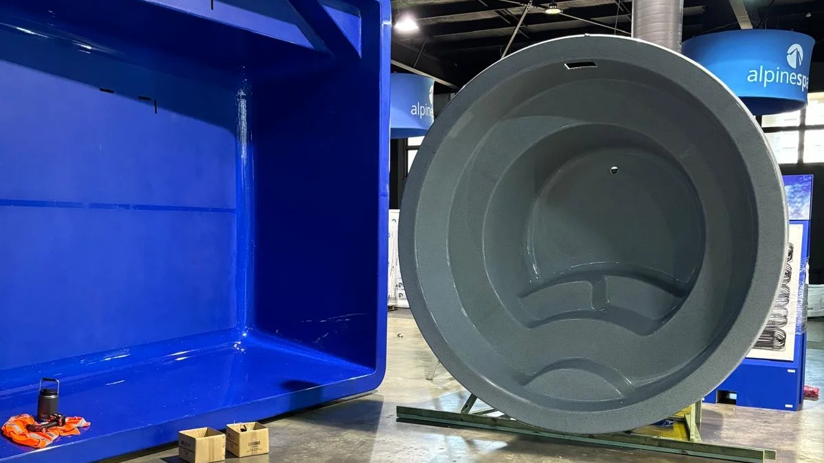 Grey fibreglass shell stood on end beside a blue shell at an MFP Easy display, showing two gelcoat colours