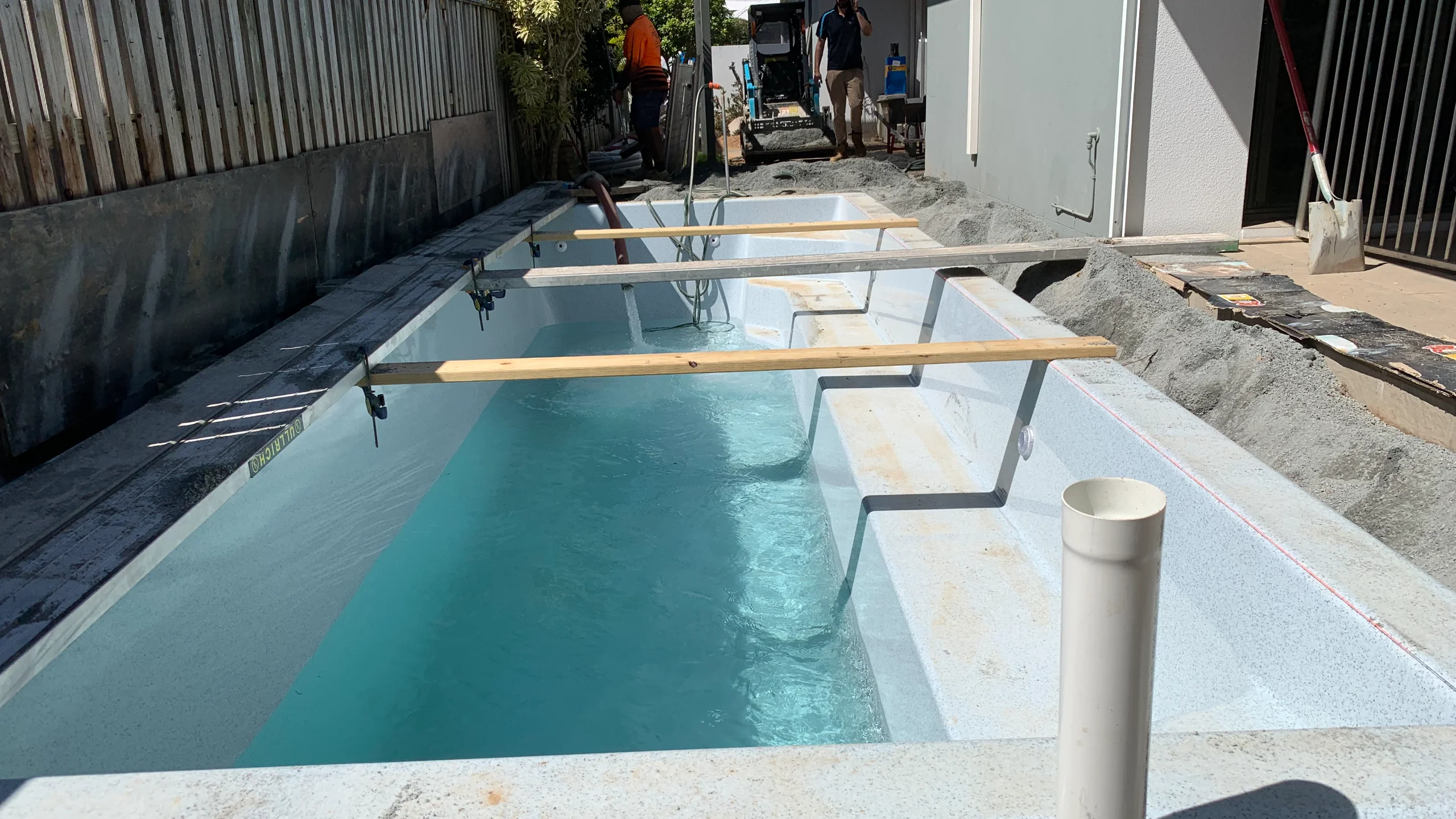 Partly filled fibreglass pool shell braced in an open excavation as the MFP Easy team backfills around it
