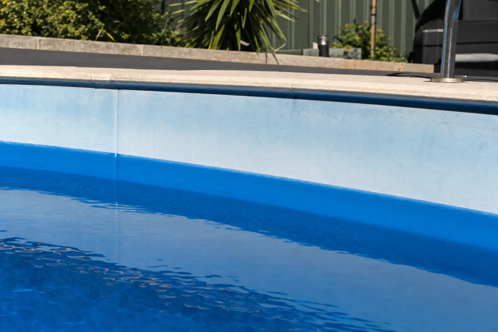 Fibreglass pool wall faded pale and chalky above the waterline with richer blue colour below — digital visualisation