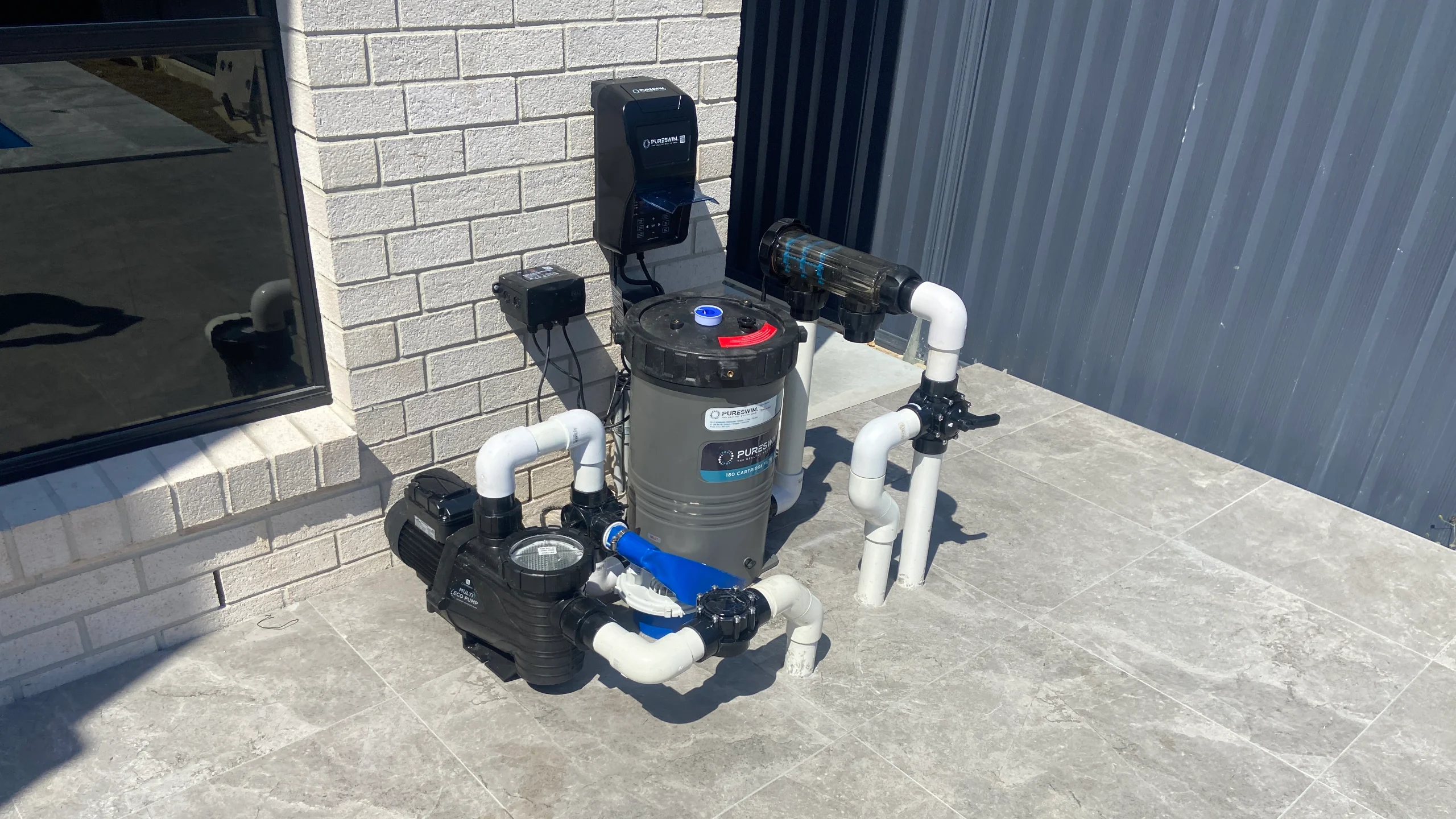 Cartridge pool filter with PureSwim tank, eco pump and white PVC plumbing on a tiled equipment pad