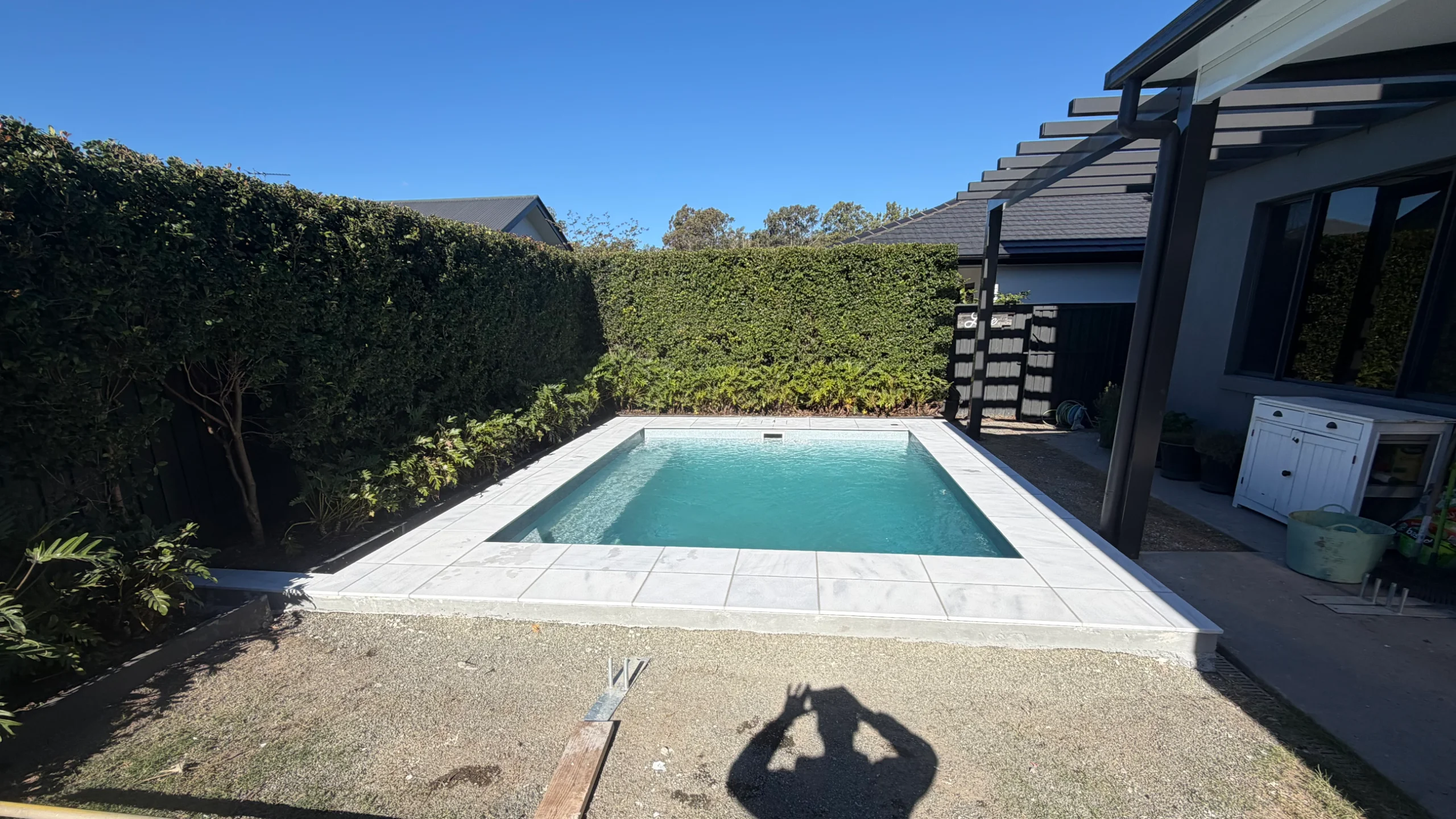 Grey stone-look porcelain pool coping laid around a rectangular fibreglass pool with visible grout lines