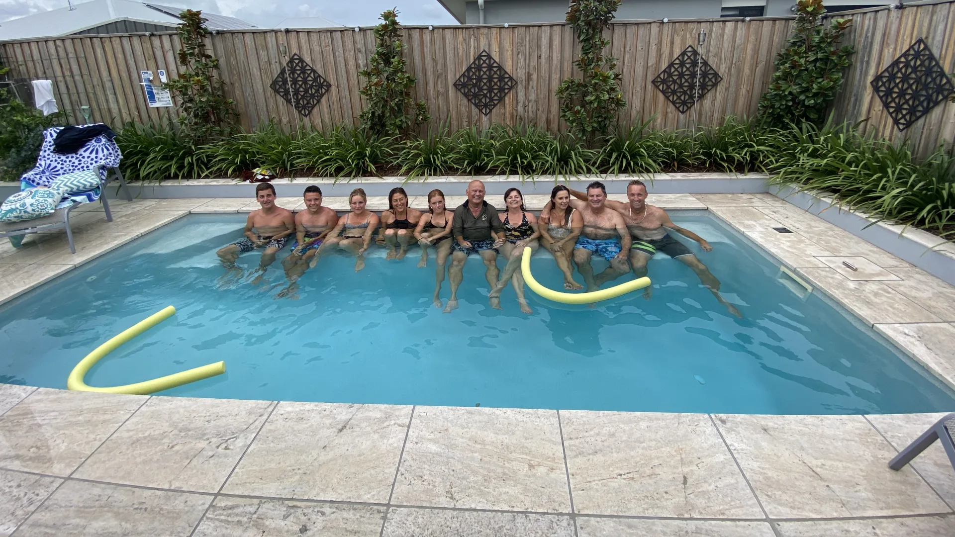 Ten family members sitting on the bench seat of a Portofino fibreglass pool