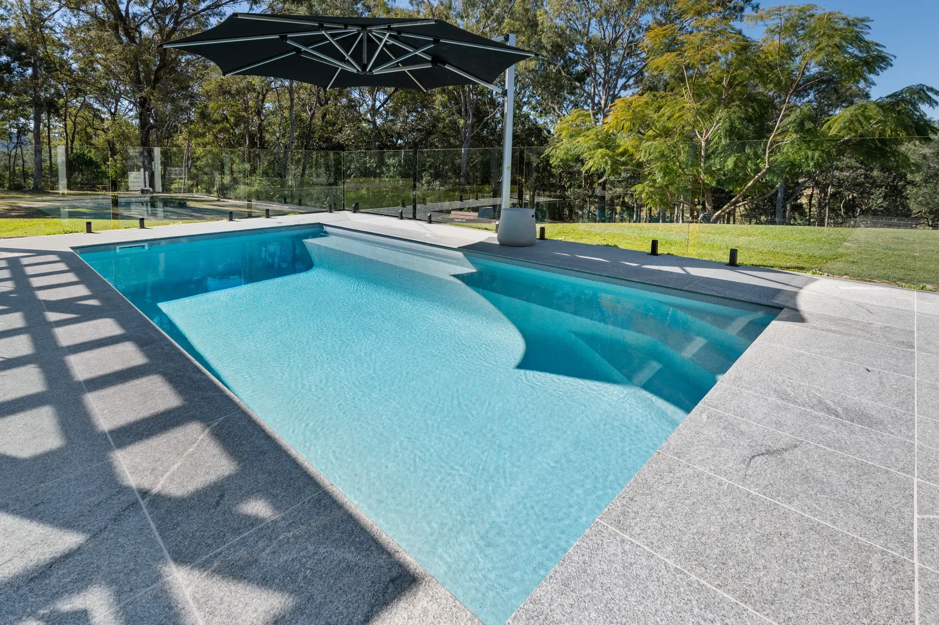 Rectangular fibreglass pool with a clean paved surround